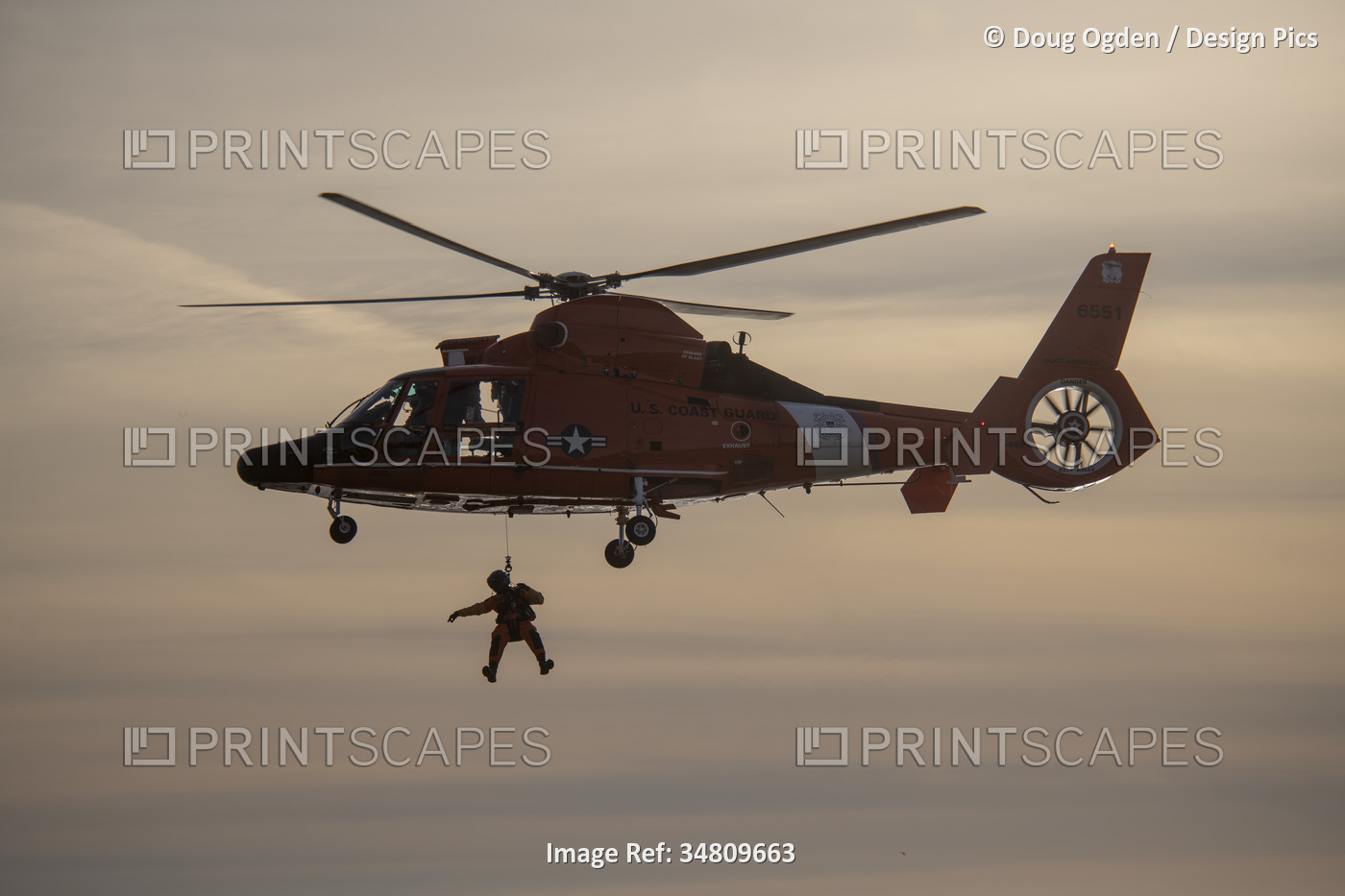 U. S. Coast Guard crew suspended below a Eurocopter MH-65 performing rescue ...