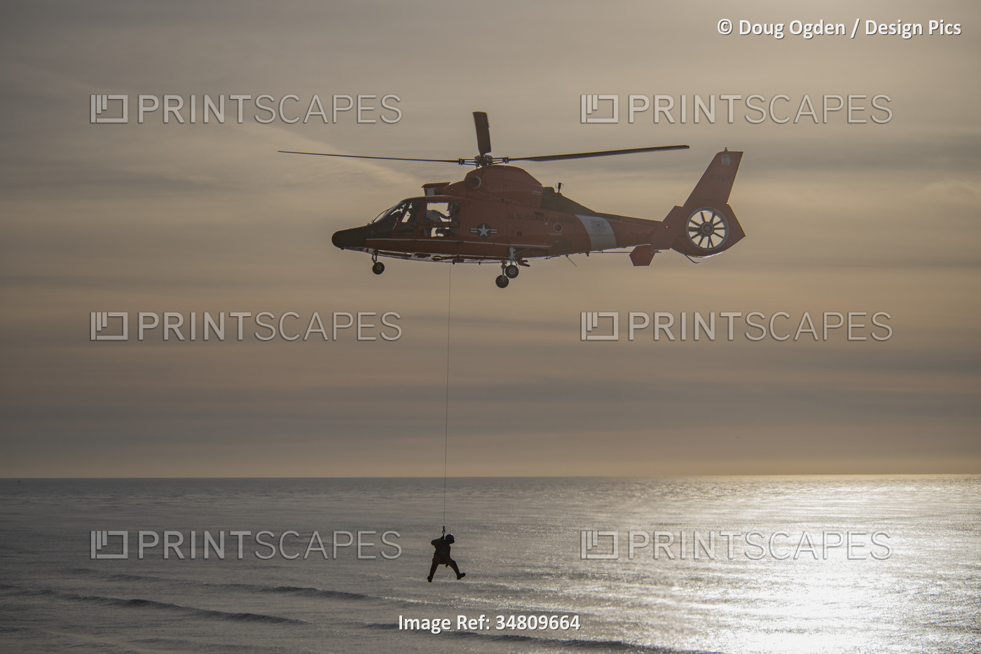 U. S. Coast Guard crew suspended below a Eurocopter MH-65 performing rescue ...